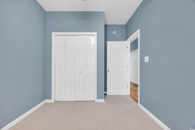 unfurnished bedroom with a closet, a textured ceiling, and light colored carpet