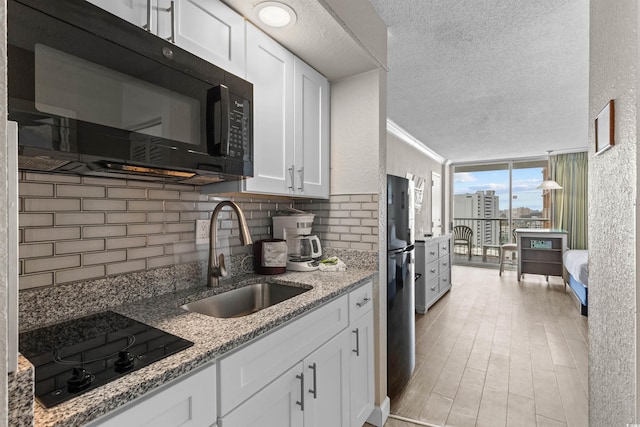 9550 Shore Dr Unit 1202, Myrtle Beach, SC 29572 - kitchen featuring black appliances, a sink, a textured ceiling, backsplash, and white cabinetry
