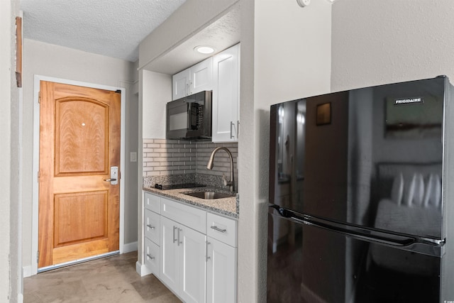 9550 Shore Dr Unit 1202, Myrtle Beach, SC 29572 - kitchen featuring black appliances, a sink, light stone countertops, white cabinets, and a textured ceiling