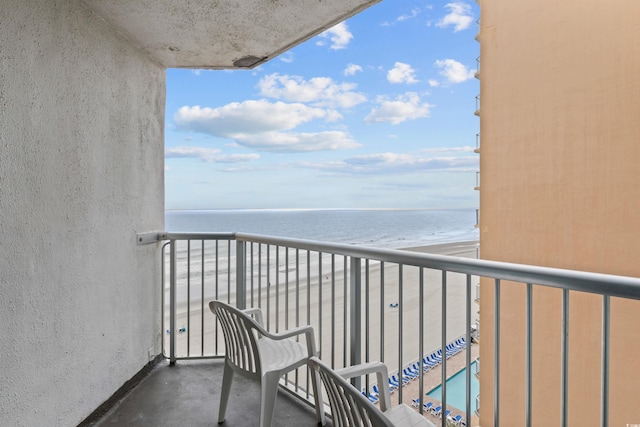 balcony with a water view and a view of the beach