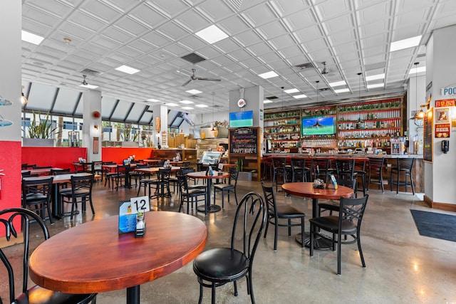 dining space with indoor bar, concrete flooring, and ceiling fan