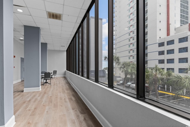 hallway featuring light hardwood / wood-style flooring, a paneled ceiling, and plenty of natural light