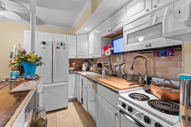 kitchen featuring white appliances, decorative backsplash, white cabinetry, ornamental molding, and light tile patterned floors