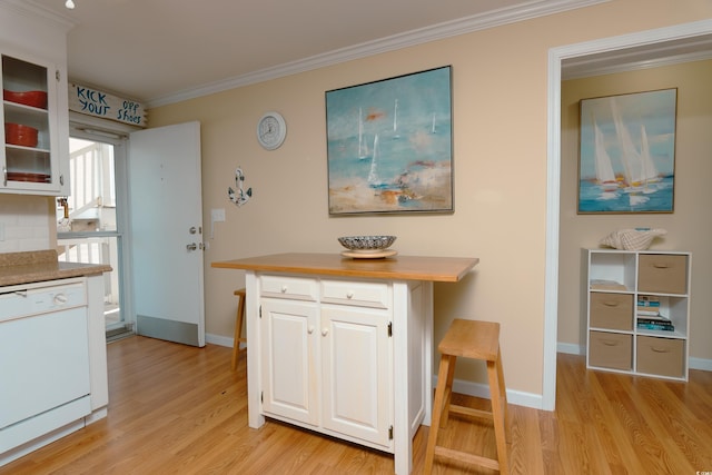 kitchen featuring white dishwasher, crown molding, white cabinets, and light hardwood / wood-style floors