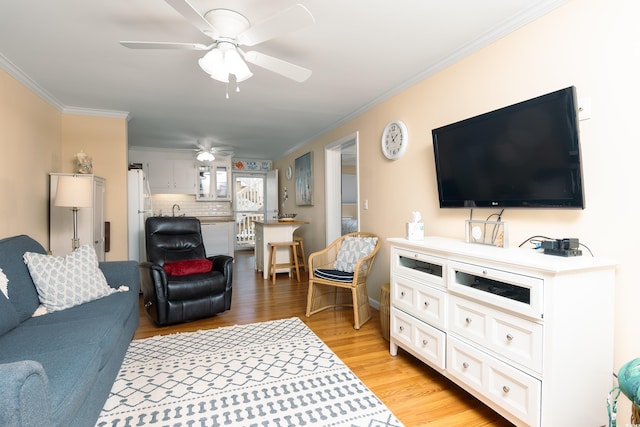 living room featuring ornamental molding, sink, light wood-type flooring, and ceiling fan