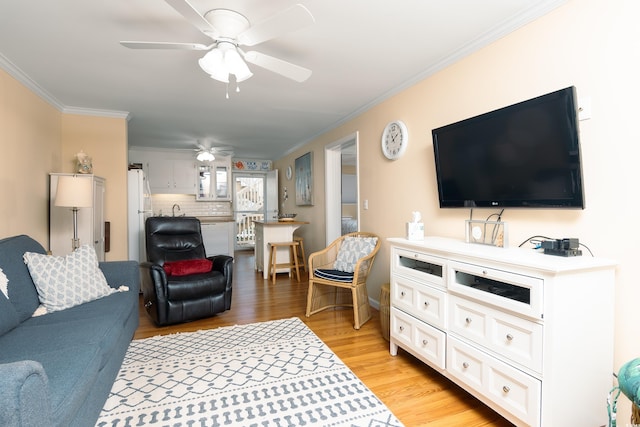 living area with ornamental molding, light wood-type flooring, and ceiling fan
