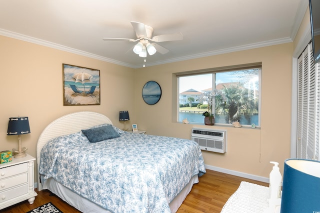 bedroom featuring ceiling fan, wood-type flooring, a wall mounted air conditioner, a closet, and crown molding