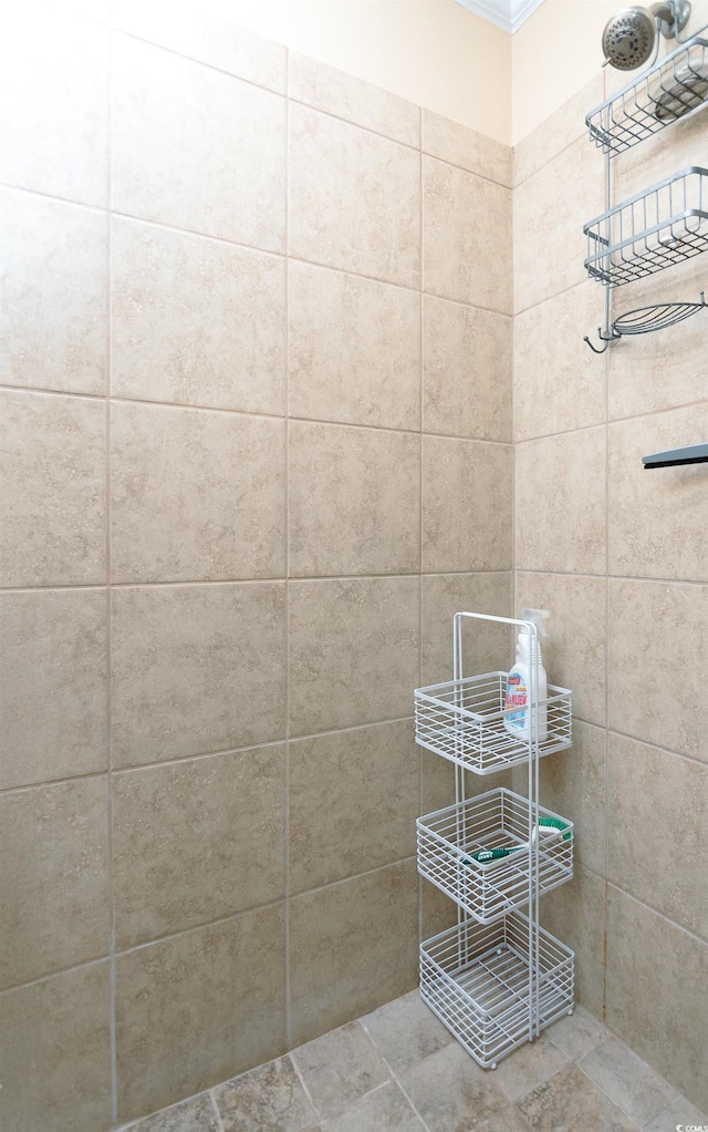 bathroom with tile patterned floors, a tile shower, and ornamental molding