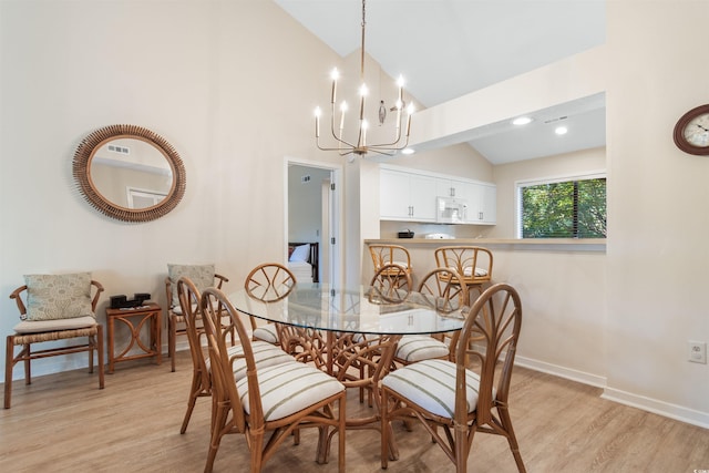 dining area featuring lofted ceiling, a notable chandelier, and light wood-type flooring