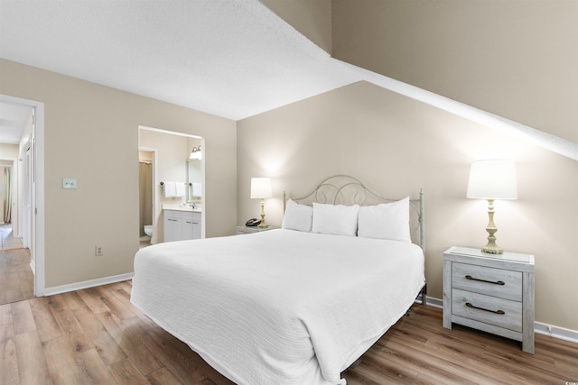 bedroom with connected bathroom and light wood-type flooring