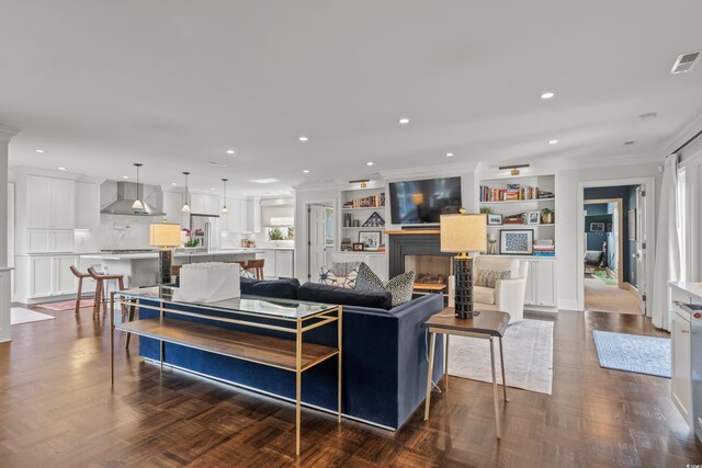 living room with ornamental molding, an inviting chandelier, dark parquet flooring, and plenty of natural light