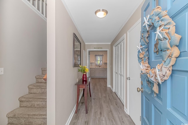 entryway with ornamental molding and light hardwood / wood-style floors