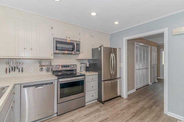 kitchen with crown molding, appliances with stainless steel finishes, light hardwood / wood-style flooring, and white cabinets