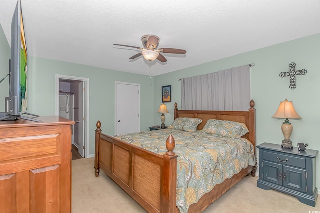 bedroom featuring a textured ceiling, light colored carpet, and ceiling fan