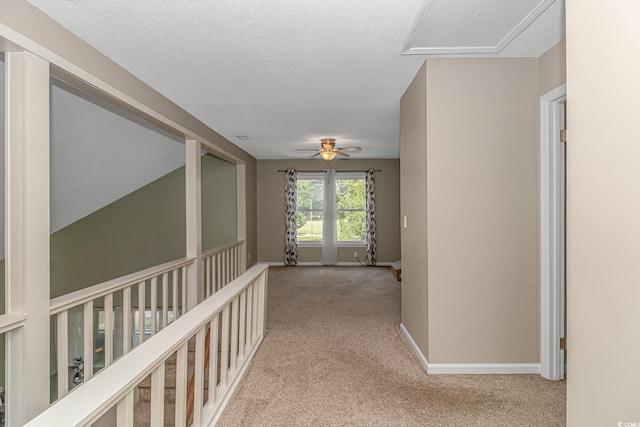 hallway with light carpet and a textured ceiling