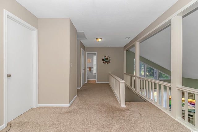 hallway with vaulted ceiling and light carpet