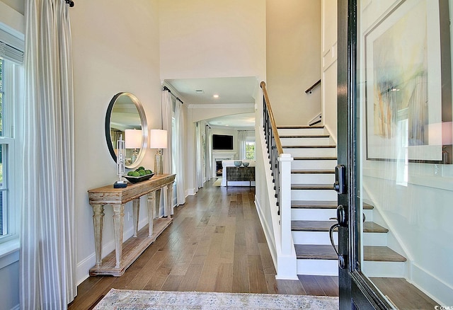 foyer entrance with a wealth of natural light, hardwood / wood-style flooring, and crown molding