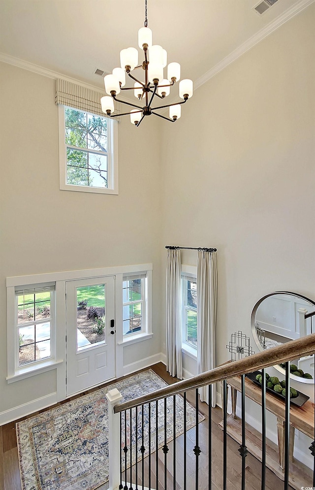 entryway featuring a wealth of natural light, an inviting chandelier, and ornamental molding