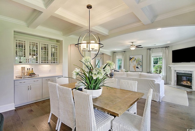 dining area featuring dark hardwood / wood-style floors, beam ceiling, ceiling fan with notable chandelier, crown molding, and coffered ceiling