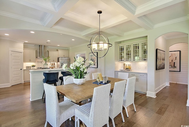 dining space with dark wood-type flooring, a chandelier, beam ceiling, and crown molding