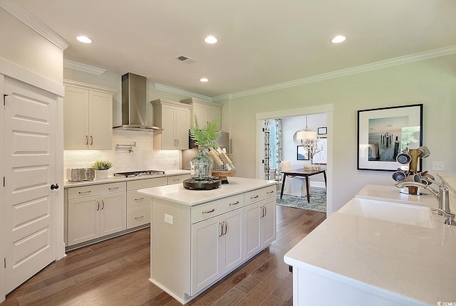 kitchen featuring a kitchen island, dark hardwood / wood-style flooring, sink, stainless steel gas stovetop, and wall chimney exhaust hood