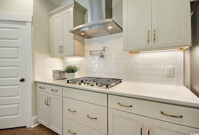 kitchen featuring dark hardwood / wood-style flooring, tasteful backsplash, stainless steel gas cooktop, and wall chimney exhaust hood