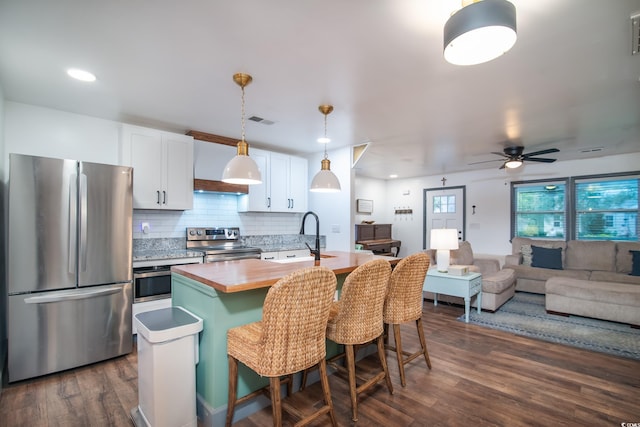 kitchen featuring white cabinetry, a kitchen island with sink, dark hardwood / wood-style flooring, and stainless steel appliances