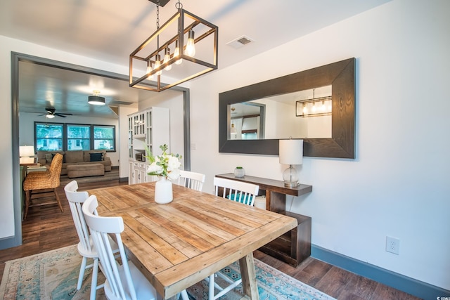 dining area with ceiling fan with notable chandelier and dark wood-type flooring