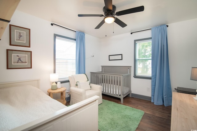 bedroom featuring ceiling fan, dark wood-type flooring, and a crib