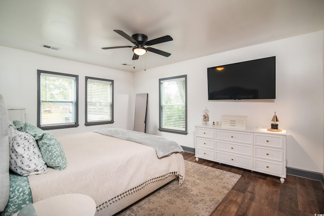 bedroom featuring dark hardwood / wood-style floors, ceiling fan, and multiple windows