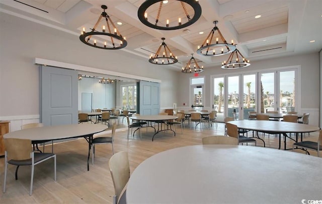 dining room with a wealth of natural light, beamed ceiling, light hardwood / wood-style floors, and coffered ceiling