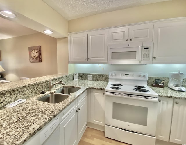 kitchen featuring sink, white cabinetry, a textured ceiling, light wood-type flooring, and white appliances