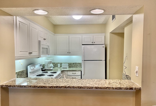 kitchen featuring light stone counters, white appliances, and white cabinets