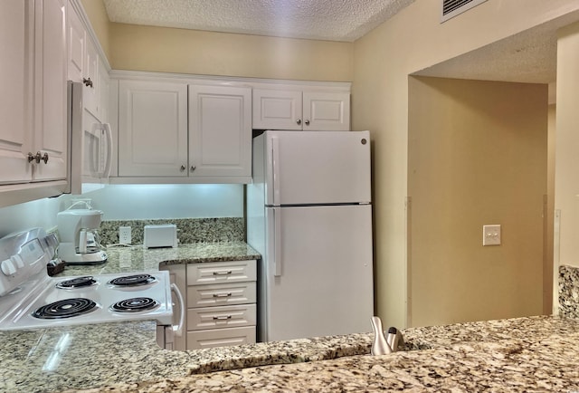 kitchen with light stone countertops, a textured ceiling, white cabinets, and white appliances