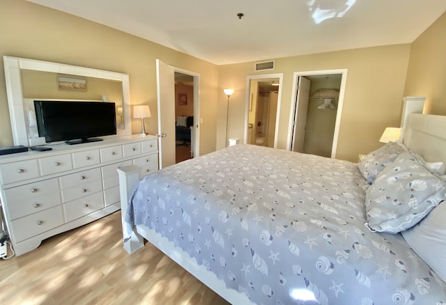 bedroom featuring a closet, a spacious closet, and light hardwood / wood-style flooring