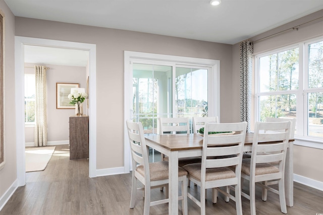 dining space featuring baseboards, wood finished floors, and recessed lighting