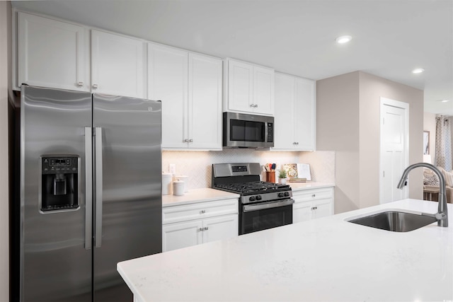 kitchen with appliances with stainless steel finishes, a sink, backsplash, recessed lighting, and white cabinets