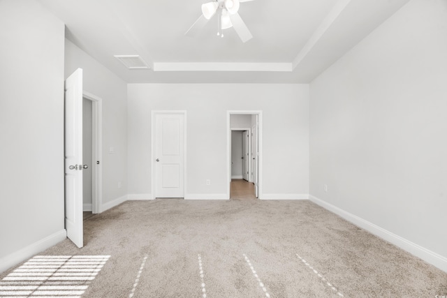 unfurnished bedroom featuring ceiling fan, a raised ceiling, and light colored carpet