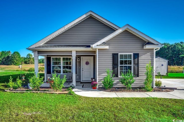 view of front facade featuring a front yard, a porch, and a shed