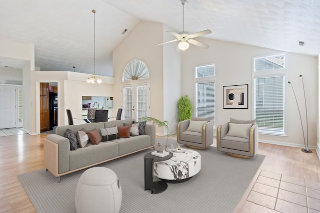 living room featuring high vaulted ceiling, light wood-type flooring, and ceiling fan with notable chandelier