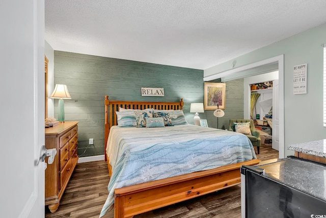 bedroom with wooden walls, a textured ceiling, a closet, and dark hardwood / wood-style flooring