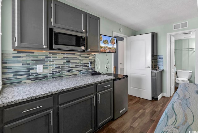 kitchen featuring dark hardwood / wood-style floors, light stone countertops, a textured ceiling, and sink