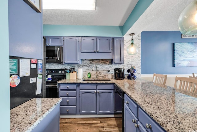 kitchen featuring backsplash, sink, black appliances, pendant lighting, and dark hardwood / wood-style flooring