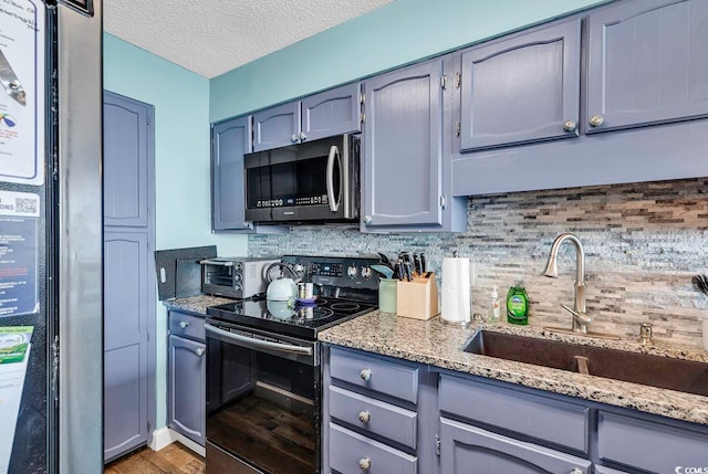 kitchen featuring light stone countertops, sink, appliances with stainless steel finishes, and light wood-type flooring