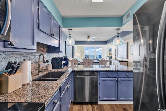 kitchen featuring sink, blue cabinets, stainless steel appliances, pendant lighting, and dark hardwood / wood-style floors