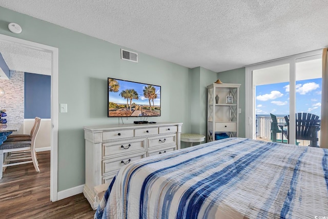 bedroom featuring a textured ceiling, access to outside, and dark hardwood / wood-style flooring