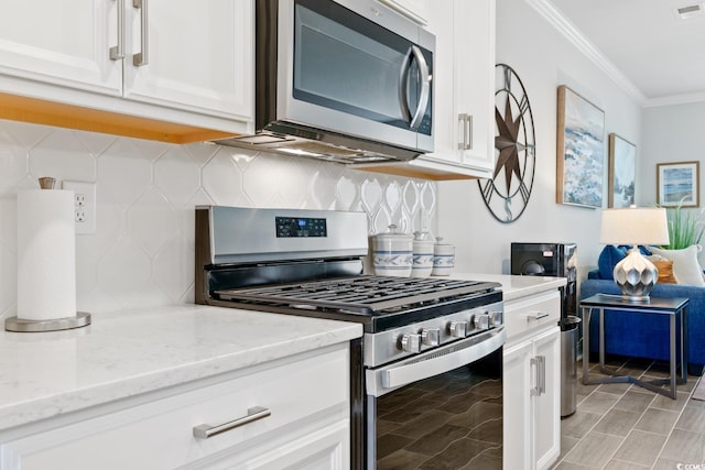 kitchen featuring light stone countertops, decorative backsplash, white cabinets, and stainless steel appliances