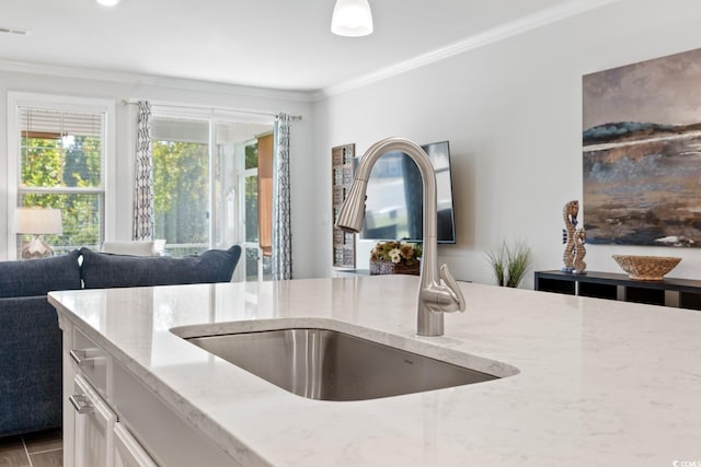 kitchen with crown molding, sink, and light stone counters