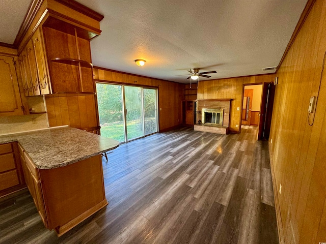 unfurnished living room with wooden walls, ceiling fan, dark hardwood / wood-style floors, and a textured ceiling