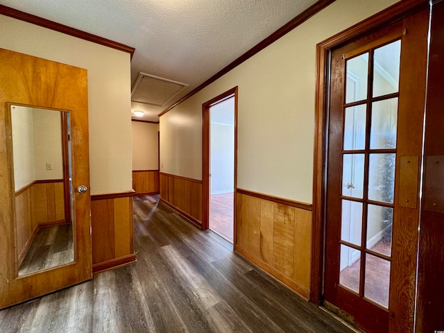 corridor featuring ornamental molding, wood walls, dark hardwood / wood-style floors, and a textured ceiling